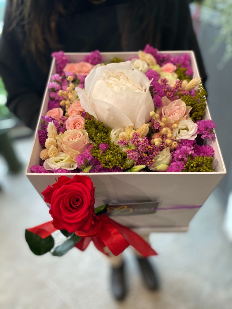 Flower box con fiori e una peonia nelle tonalità del rosa, con l'aggiunta di una rosa stabilizzata nella confezione.